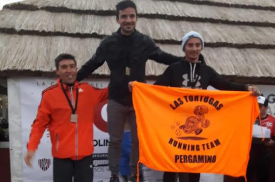 Marcos Misiewicz (a la derecha) en la premiación de su categoría con la bandera de su grupo de amigos Las Tortugas Running Team